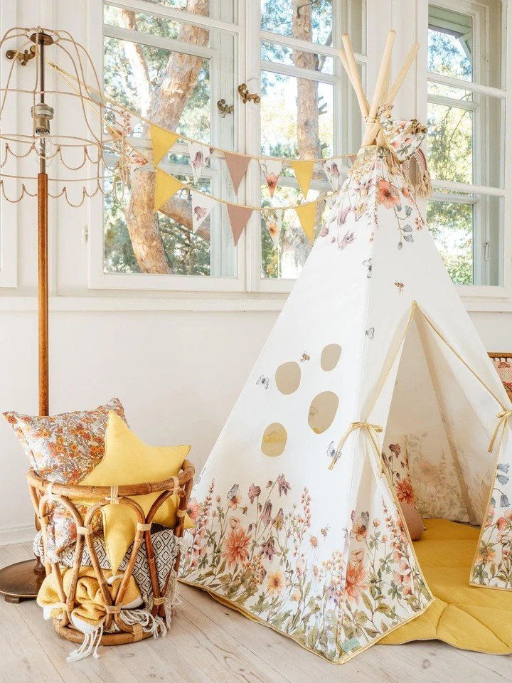 2. Cozy children's teepee tent with floral print and yellow interior, styled in a bright room with decorative bunting and cushions