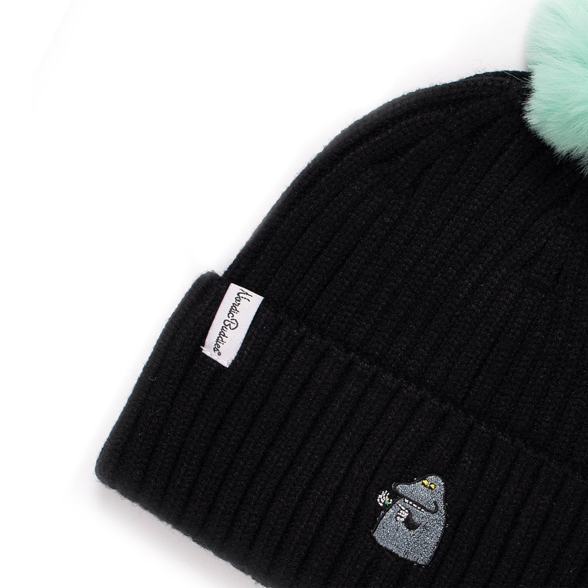 2. Close-up of black kids' beanie with mint green pom-pom, showing Moomin character embroidery and NordicBuddies label
