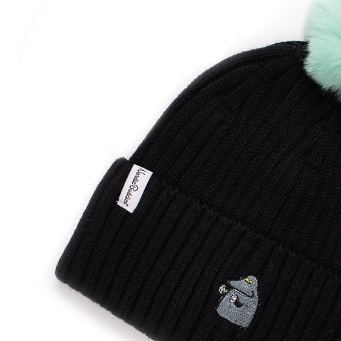 2. Close-up of black kids' beanie with mint green pom-pom, showing Moomin character embroidery and NordicBuddies label