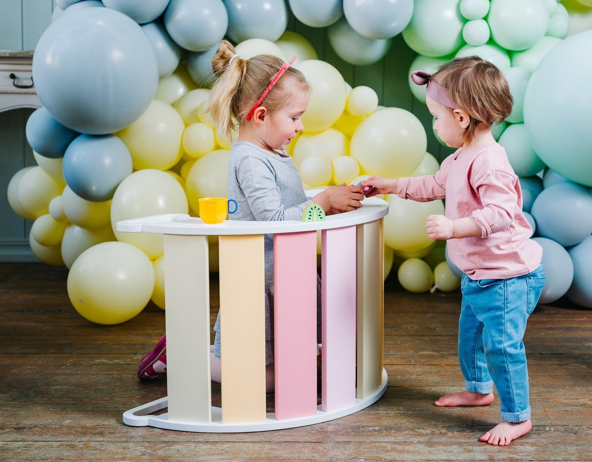 1. Two children playing with colorful rainbow climber surrounded by balloons