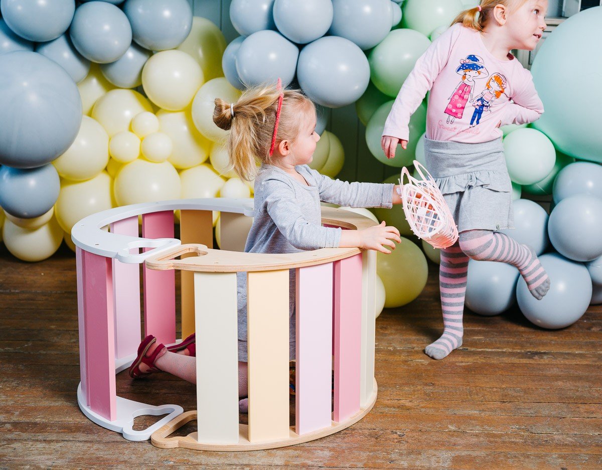1. Two children playing with colorful rainbow climber surrounded by balloons