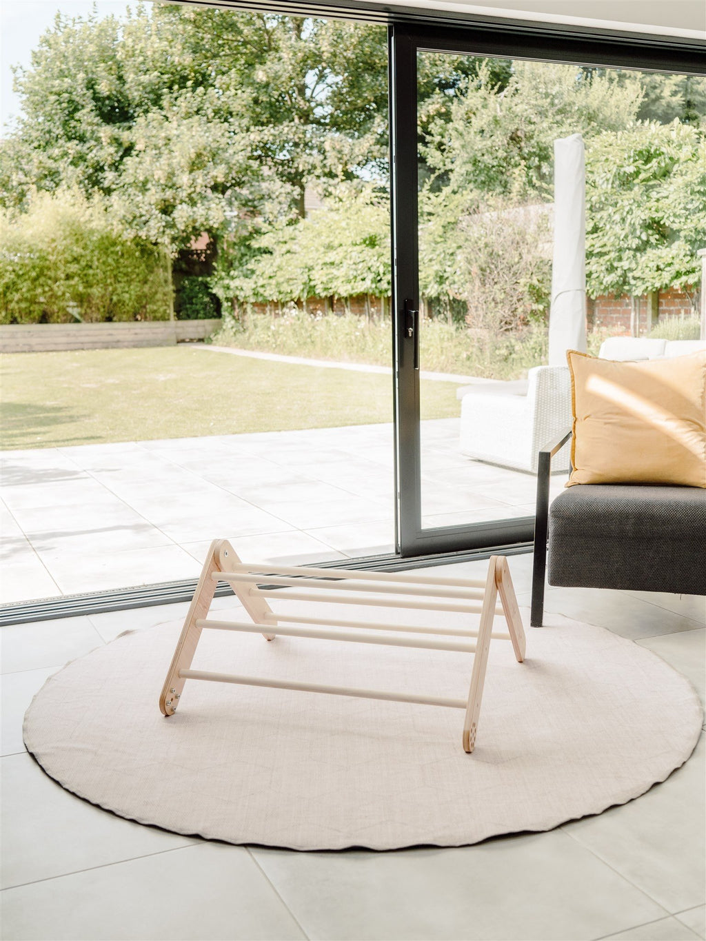 4. Family-scl Pikler Triangle in birch plywood on a round rug near a large window, highlighting its aesthetic appeal and suitability for indoor use.