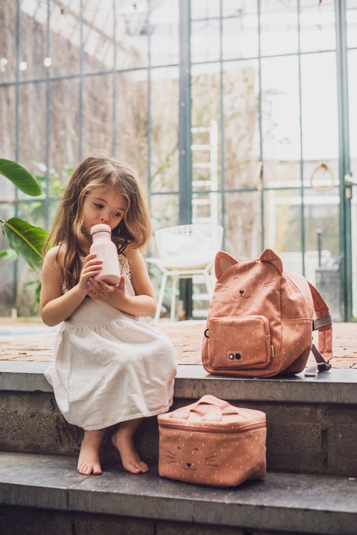 6. Young girl with Trixie Baby Mrs. Cat thermal lunch bag and matching backpack, sitting on steps in glasshouse setting