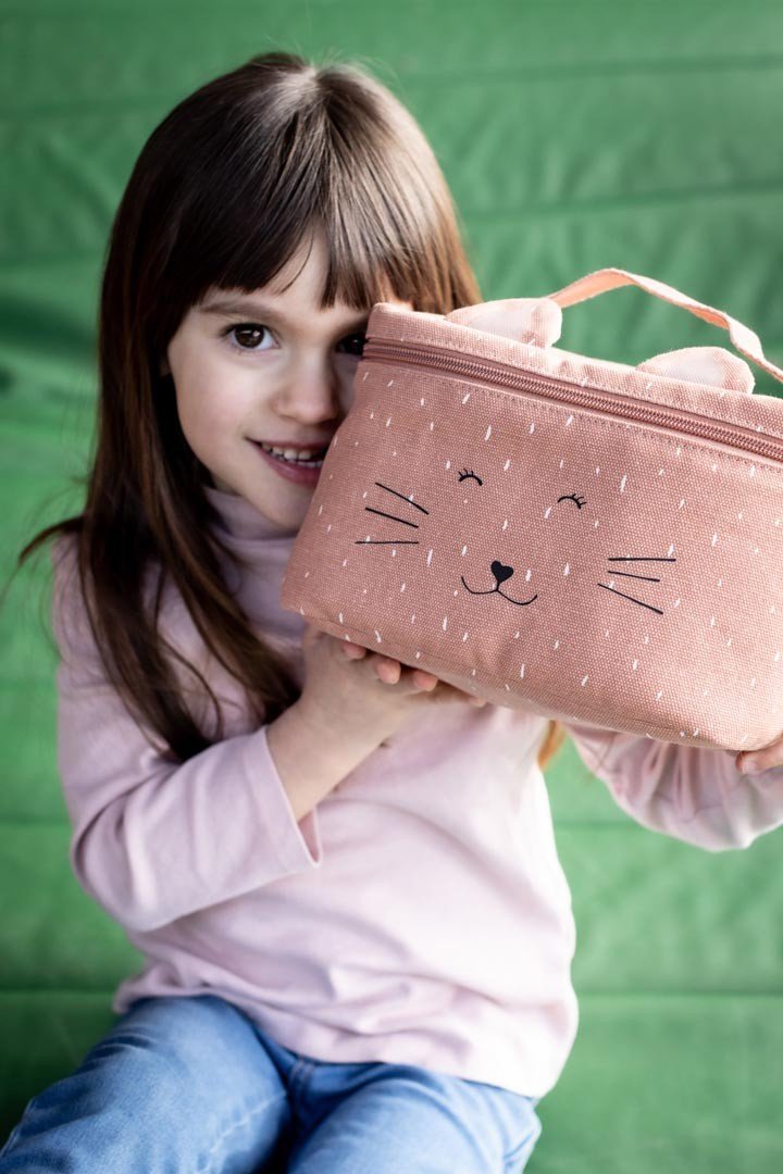 1. Young girl holding Trixie Baby Mrs. Cat thermal lunch bag with playful cat face design, sitting on green background