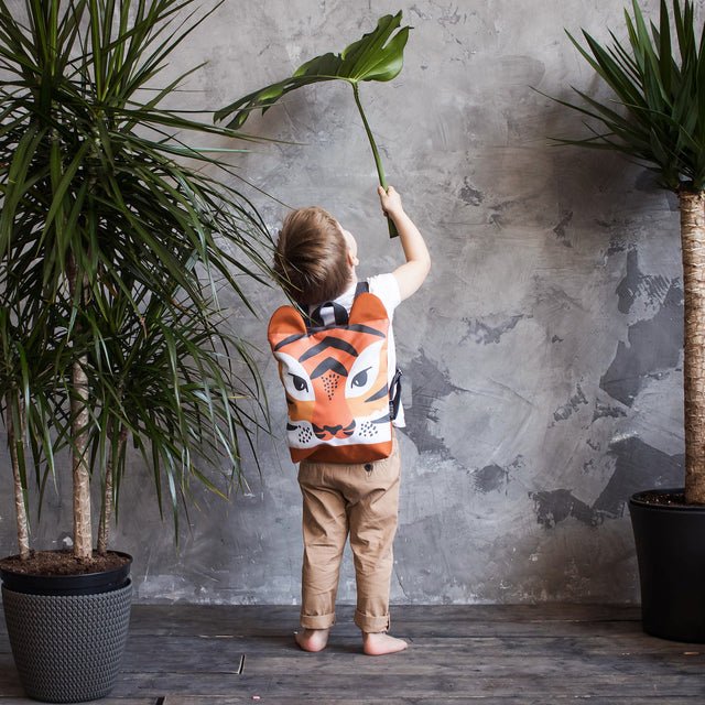 3. Child indoors with Muni Tiger backpack, emphasizing playful tiger pattern and comfortable fit