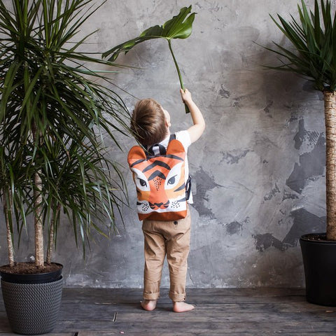 3. Child indoors with Muni Tiger backpack, emphasizing playful tiger pattern and comfortable fit