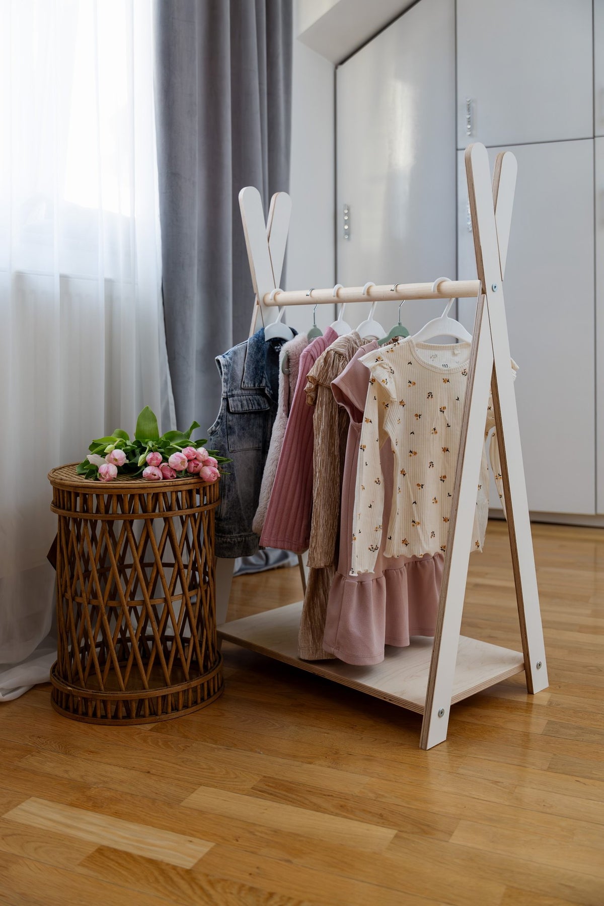 1. Children's white Tipi clothing rack by MeowBaby in a room setting with dresses and a wicker basket with flowers