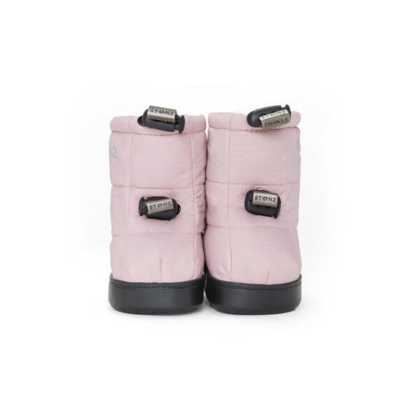 2. Stonz toddler puffer booties in haze pink with black soles shown from back in studio