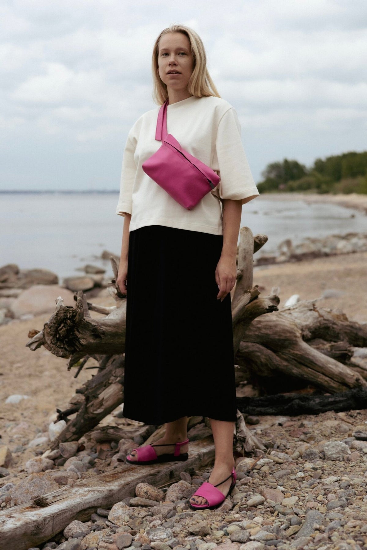 1. Woman wearing Omaking TOKU Lisbon pink leather bag across her shoulder on a beach