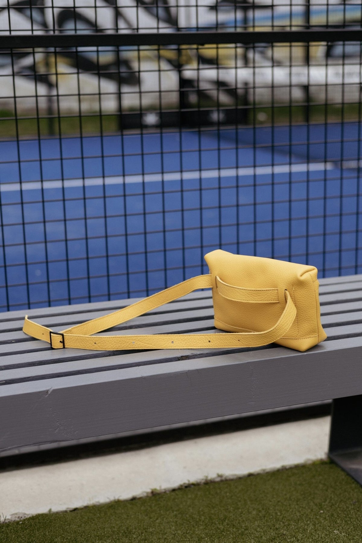 2. Yellow TOKU Lisbon bag by Omaking on a bench, showcasing adjustable strap and minimalist design