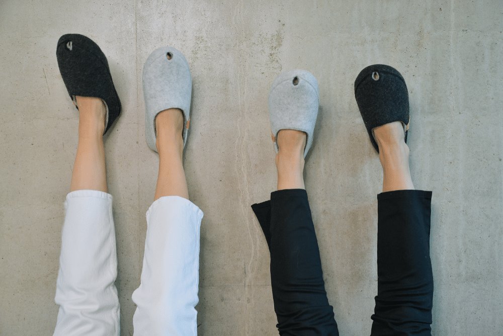 1. Lifestyle image of three people wearing TOKU Budapest slippers in white and black, showing cozy fit and style