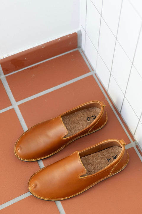 2. Lifestyle image of TOKU London Classic Shoes in Ocre placed on terracotta tiles, highlighting the shoe's design and color