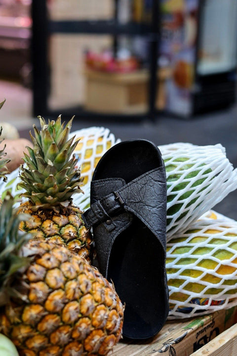 1. TOKU Rome Vegan Sandals in black displayed with pineapples, highlighting sustainable Piñatex material