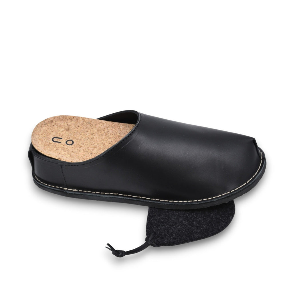 3. Close-up of unisex black slip-on shoe with cork insole and felt polishing cloth, highlighting interior details