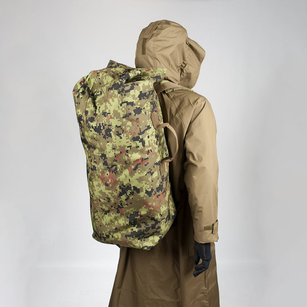 2. Model wearing a large camouflage backpack over a brown coat, shown from the back in studio setting