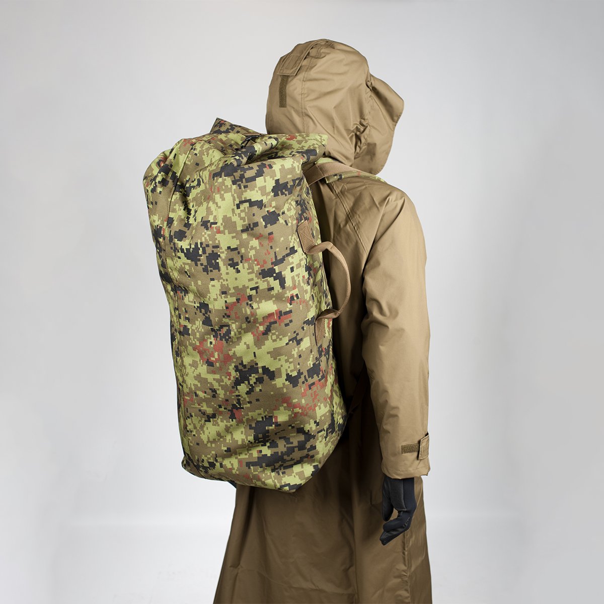 2. Model wearing a large camouflage backpack over a brown coat, shown from the back in studio setting