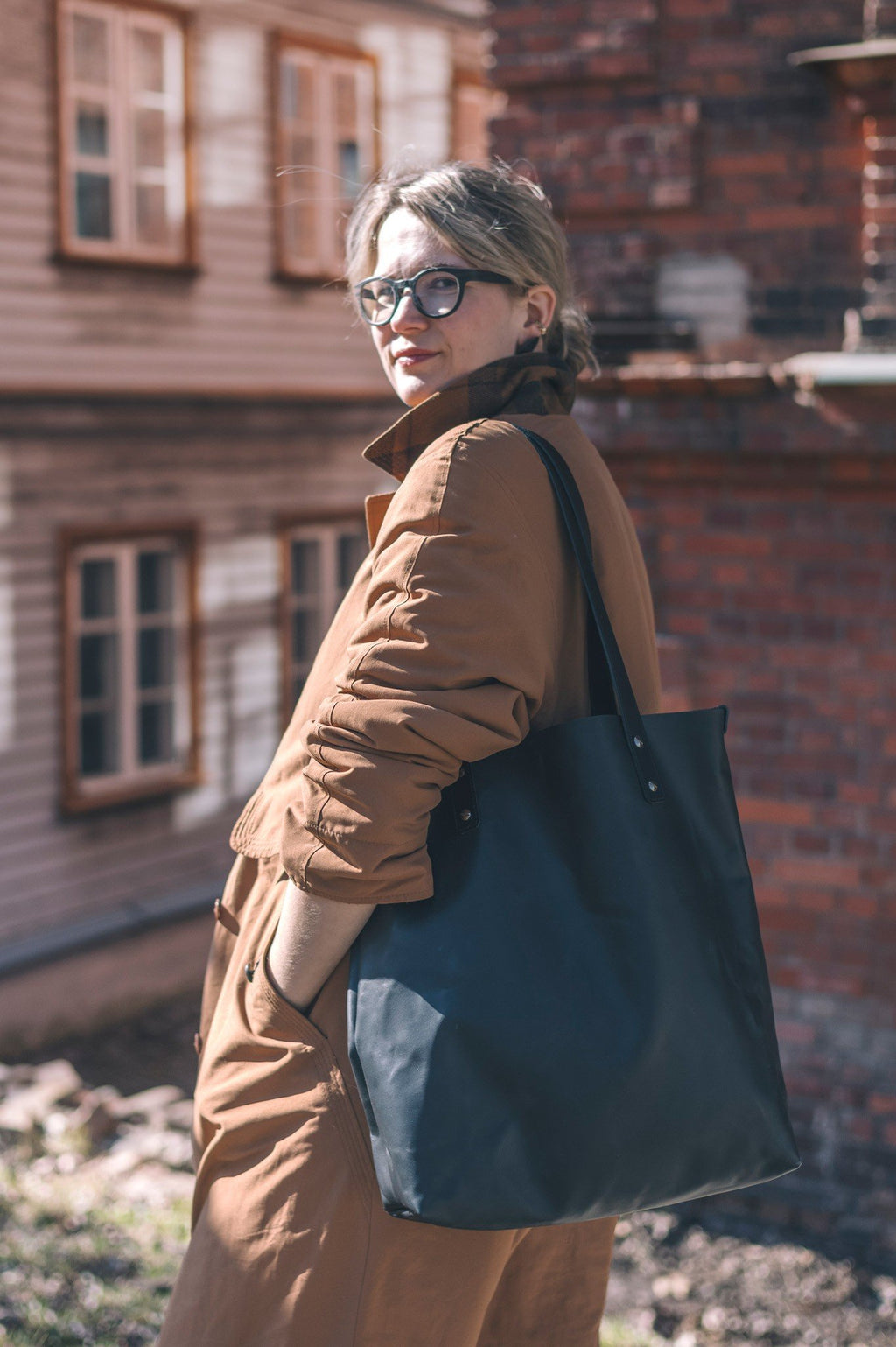 1. Woman wearing brown coat holding black Stella Soomlais tote bag in urban setting