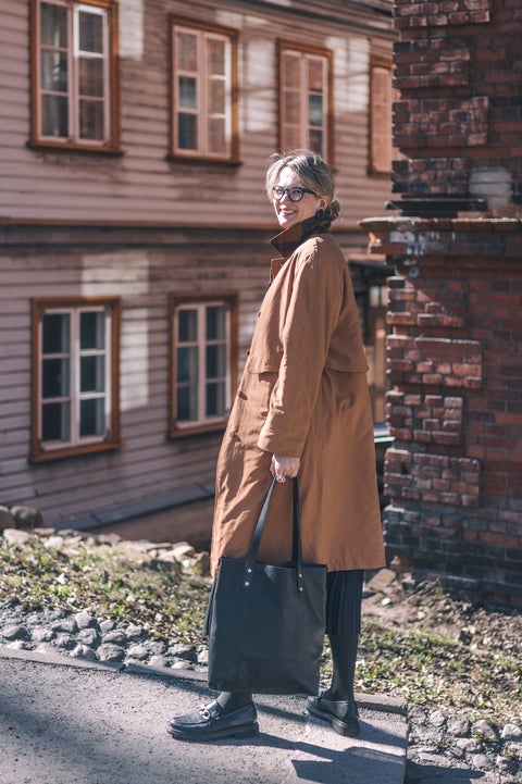 1. Woman in brown coat walking with black Stella Soomlais tote bag in residential area