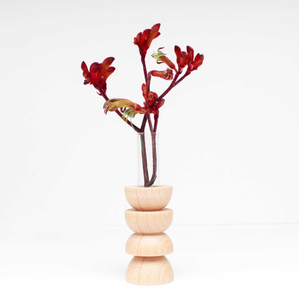 2. Studio shot of Totem Wooden Vase - Medium Nº 4 by 5mm Paper with red flowers, featuring beech wood base and glass tube