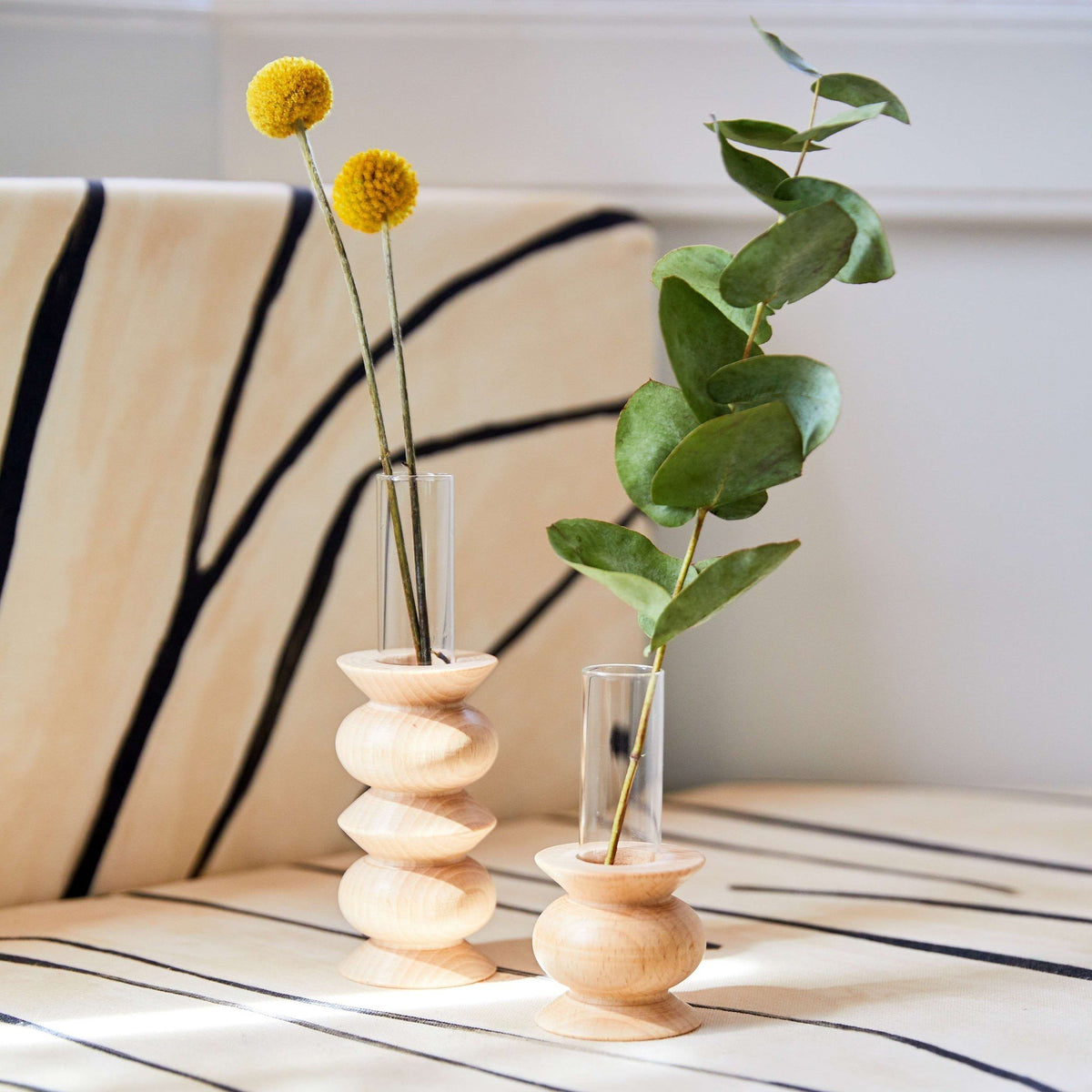 5. Pair of Totem Wooden Vases by 5mm Paper with flowers on a striped surface, lifestyle setting