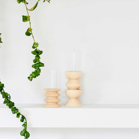 1. Lifestyle image of Totem Wooden Vase - Short Nº 2 by 5mm Paper, displayed on a shelf with greenery, showcasing its beech wood base and glass tube