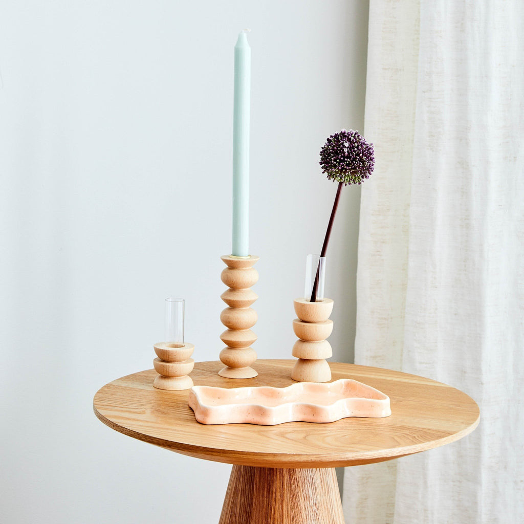 1. Lifestyle image of Totem Wooden Vase - Short Nº 4 by 5mm Paper on a wooden table with a candle and decorative items