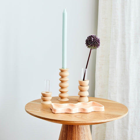 1. Lifestyle image of Totem Wooden Vase - Short Nº 4 by 5mm Paper on a wooden table with a candle and decorative items