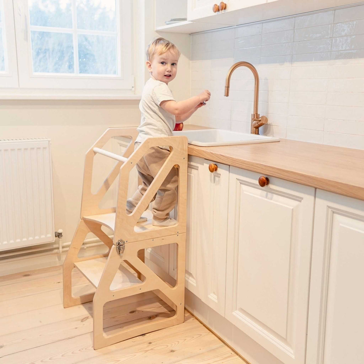 1. Toddler using natural birch kitchen tower at sink in bright kitchen