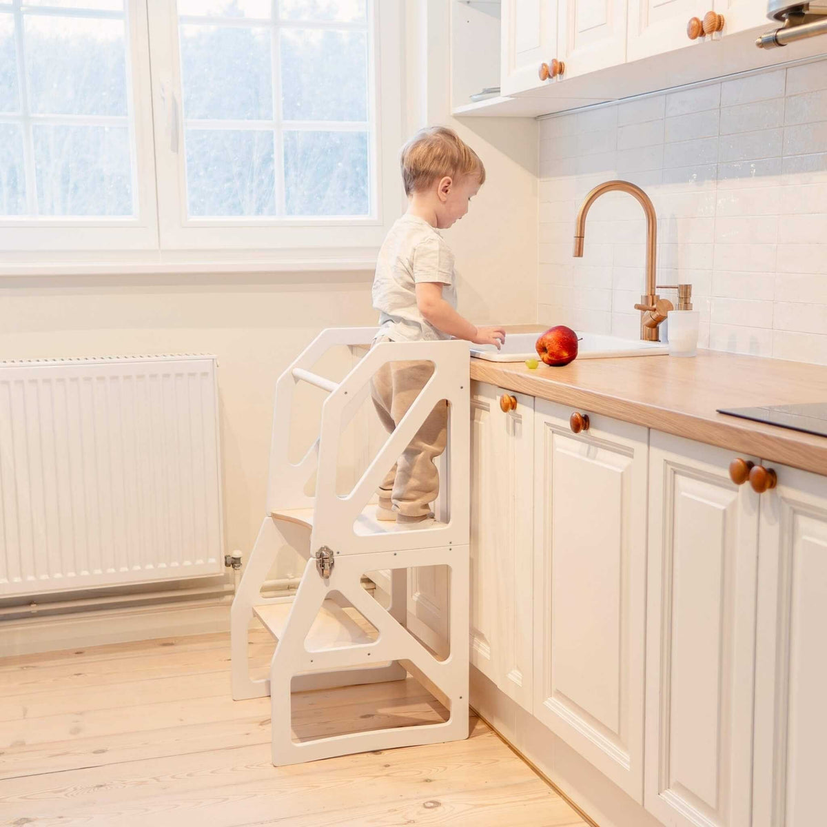1. Toddler using white kitchen tower at sink in bright kitchen