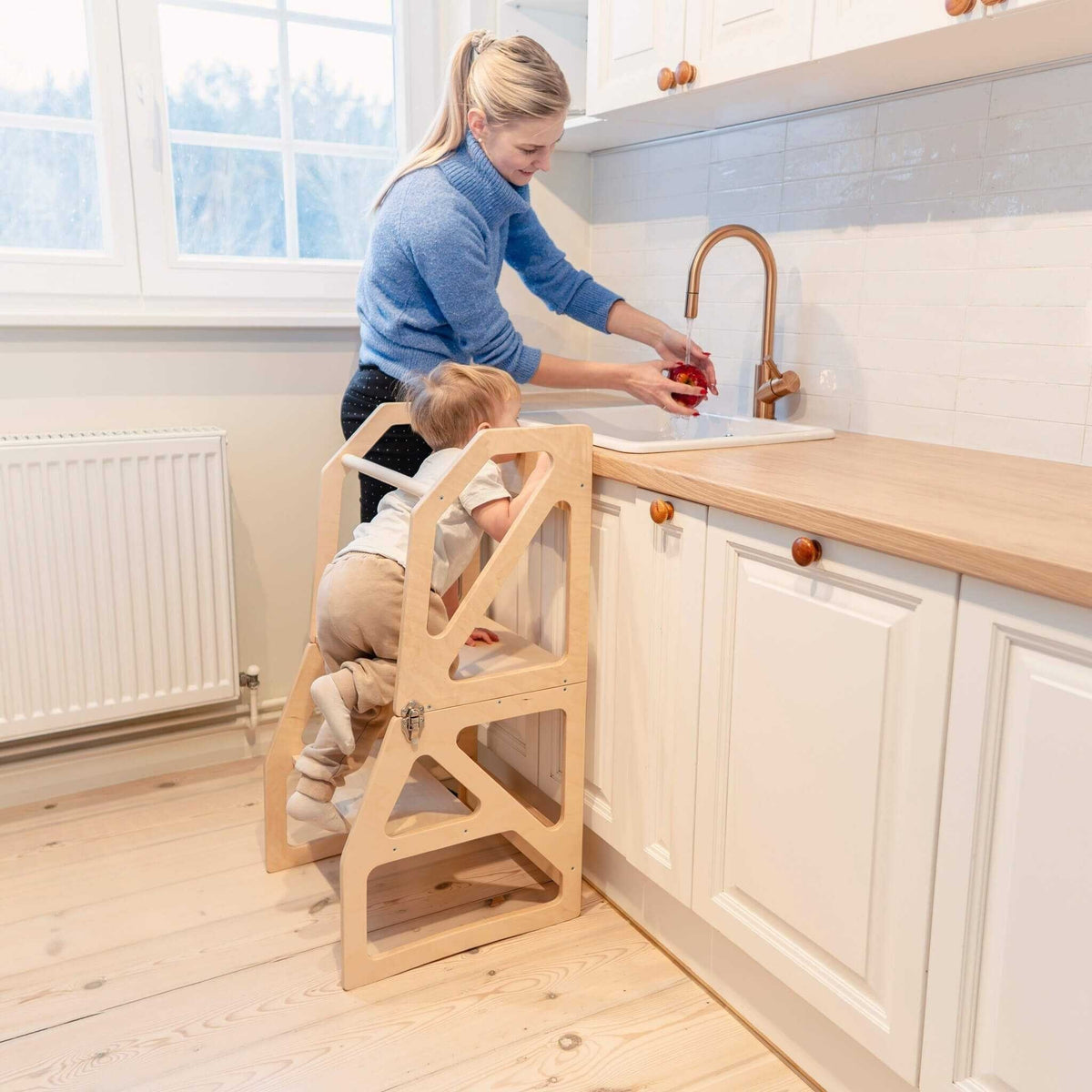 1. Woman and toddler using natural birch kitchen tower at sink in bright kitchen