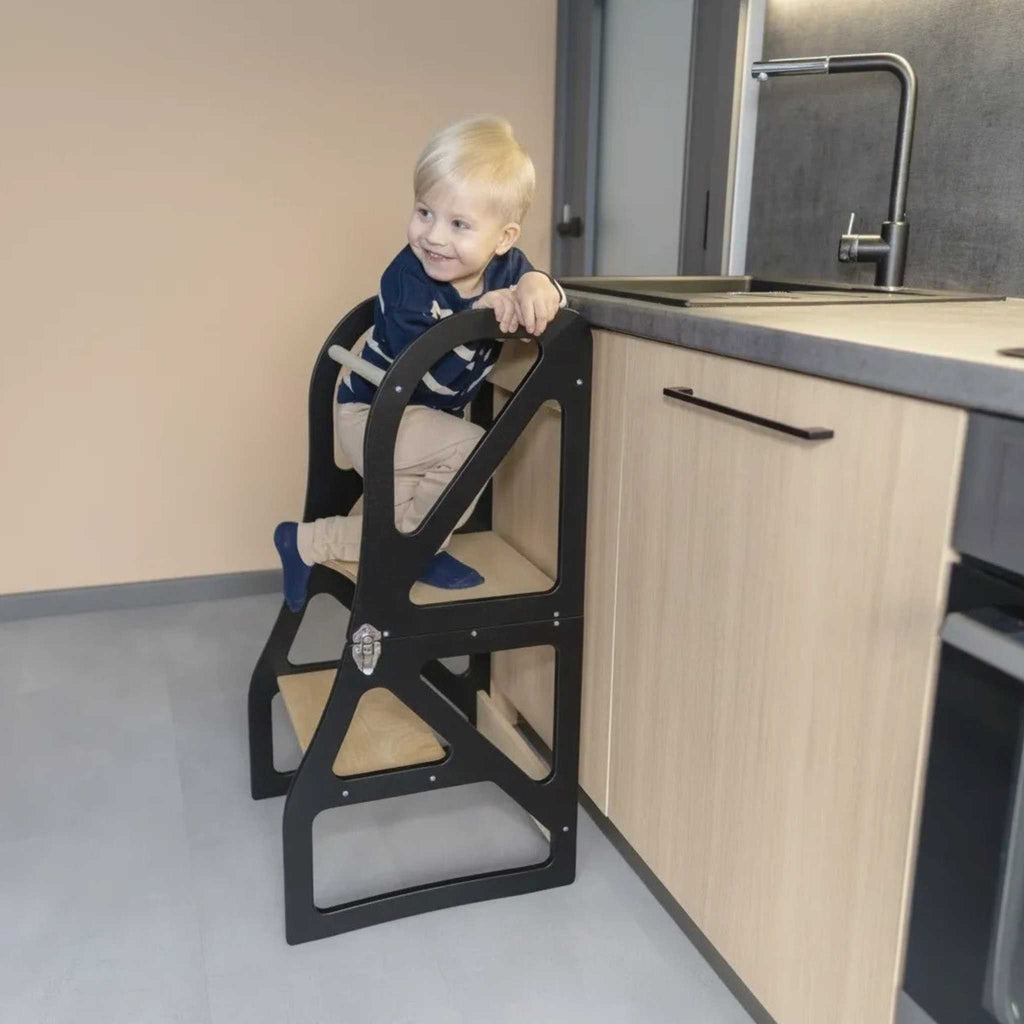 1. Child climbing black transformable kitchen tower next to a kitchen counter