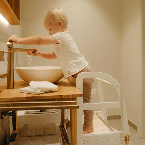 1. Child using white transformable kitchen tower at bathroom sink