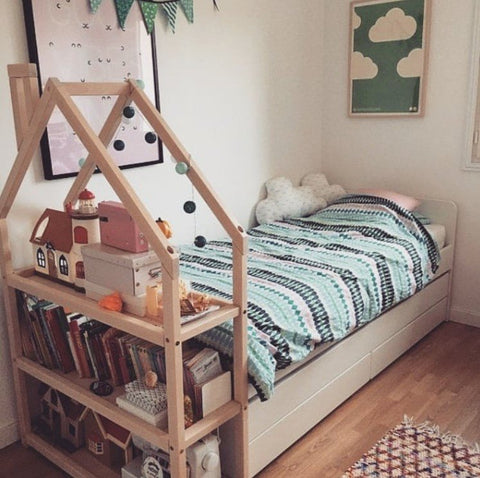 1. Natural wood house-shaped shelf in bedroom with books and toys next to bed