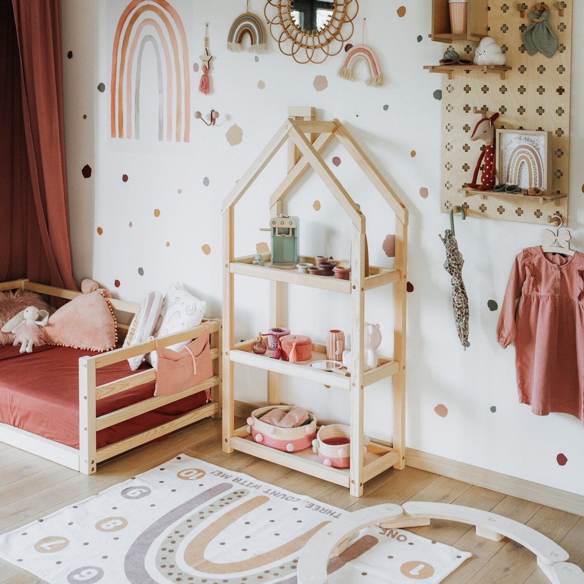 1. Natural wood house-shaped shelf in children's room with pink bed and rainbow decor