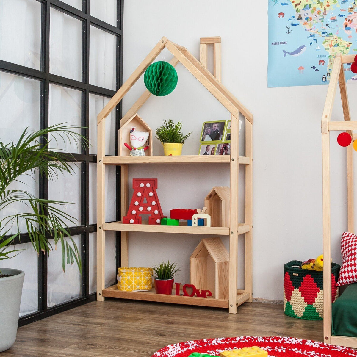 2. House-shaped shelf in playroom with colorful toys and plants on wooden floor
