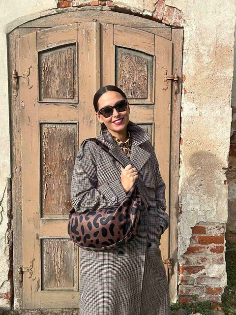 1. Woman holding Garbanota Classic Leopard Hobo Bag in indoor setting, showcasing adjustable strap and leopard print