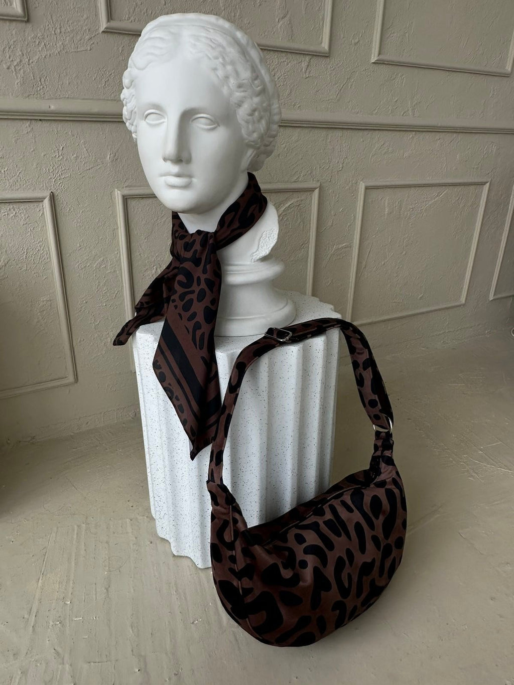 3. Woman posing with Garbanota Classic Leopard Hobo Bag in front of rustic door, highlighting bag's design