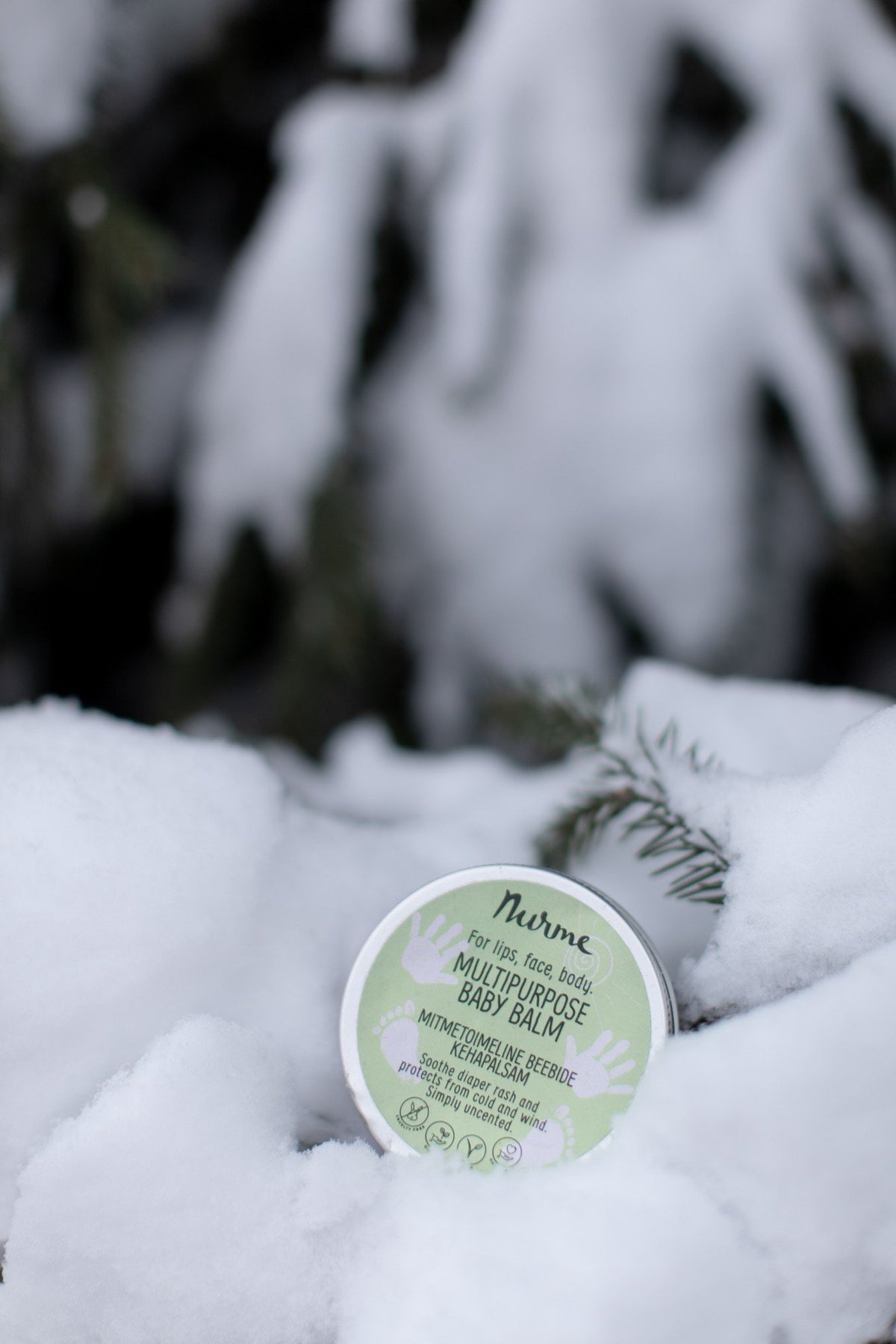 3. Nurme multipurpose baby balm tin nestled in snow with evergreen branches