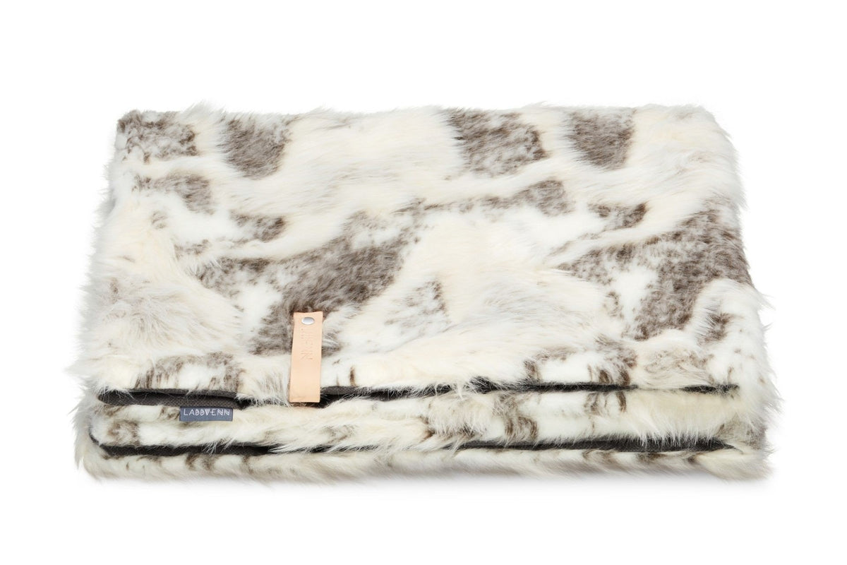 2. Labbvenn Tösse brown and white faux fur blanket folded with leather strap on white background