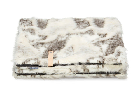 2. Labbvenn Tösse brown and white faux fur blanket folded with leather strap on white background