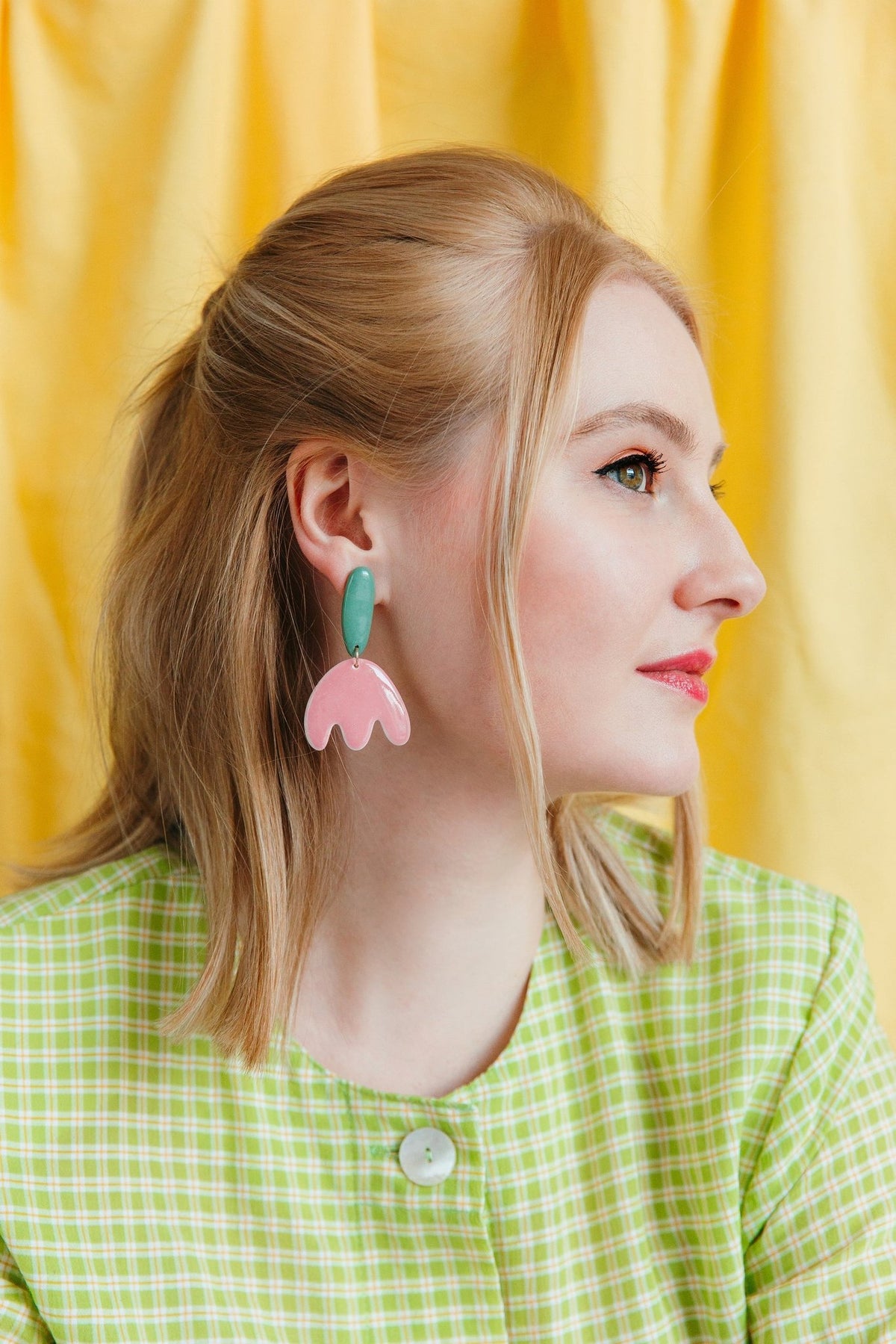 2. Side view of woman wearing Rozenthal Porcelain Tulip Earrings, showcasing pink and green tulip design, paired with a green checkered dress