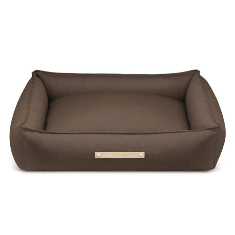 2. Brown Labbvenn Töve dog bed with high sides and elongated shape, featuring a sophisticated fabric texture and leather belt, shown in studio setting