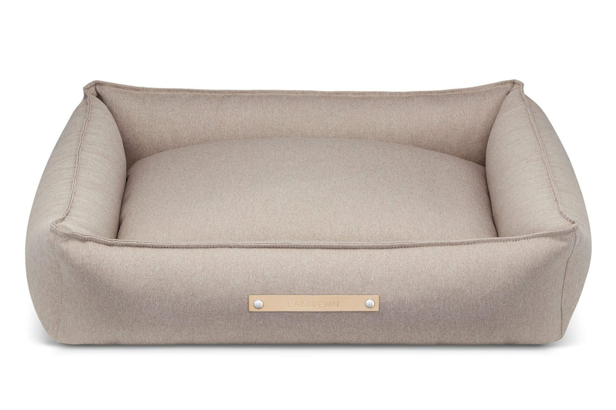 2. Beige Labbvenn Töve dog bed with high sides and leather logo tag shown in studio setting