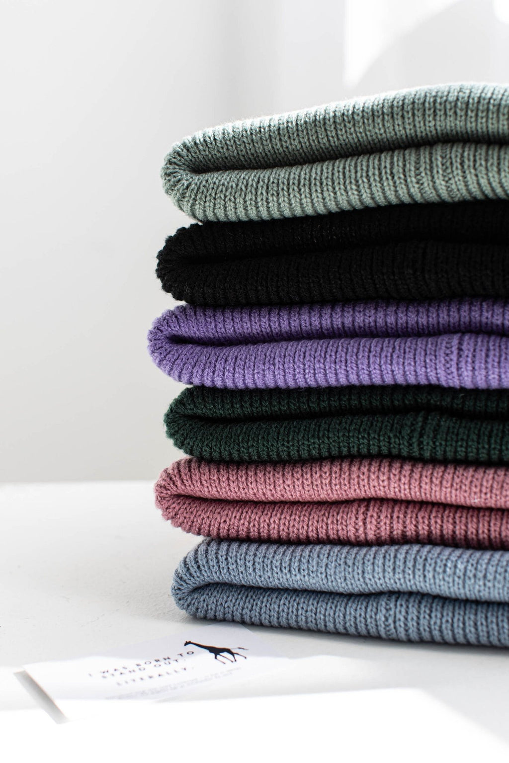2. Stack of folded beanies in various colors including purple, pink, and green, showcasing ribbed texture