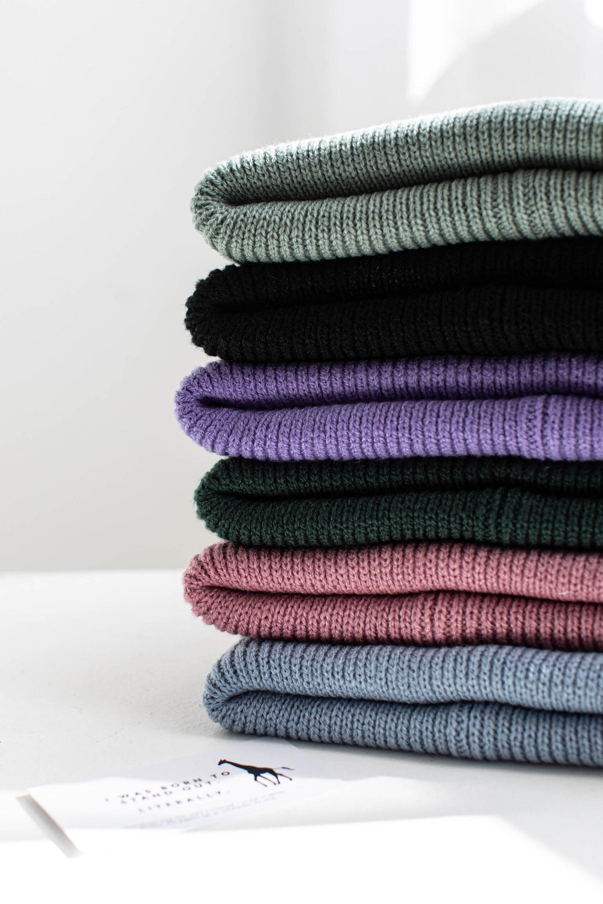 2. Stack of folded beanies in various colors including purple, pink, and green, showcasing ribbed texture
