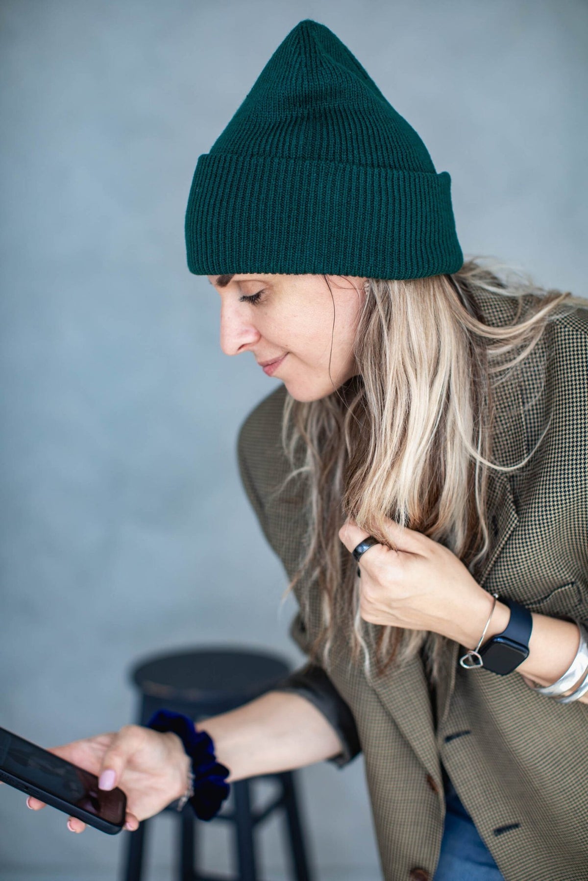 6. Woman wearing dark green beanie, looking at phone, casual style with blazer