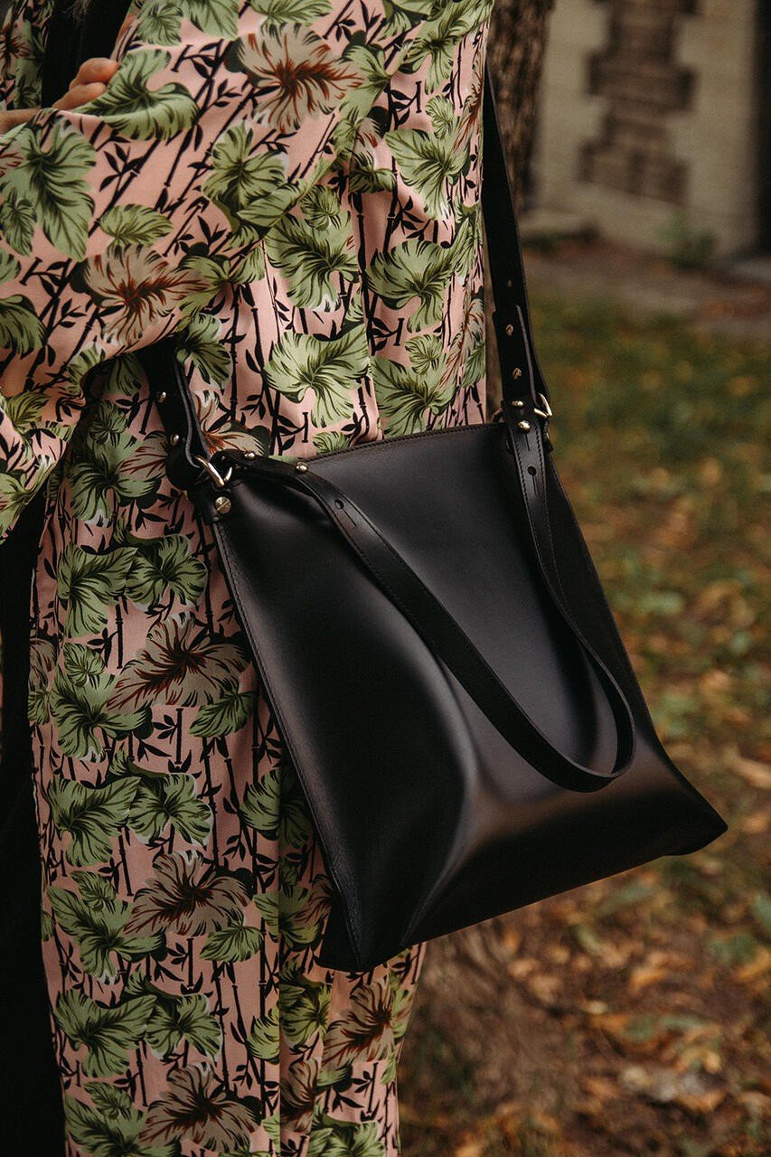 3. Detail of black Stella Soomlais Escape Artist handbag with adjustable strap against floral dress
