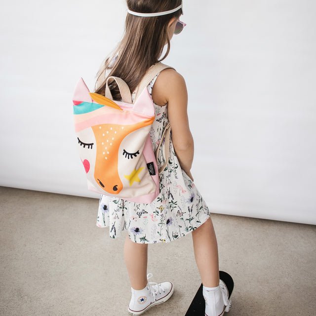 9. Girl wearing MUNI Unicorn backpack with skateboard, emphasizing playful design and practicality