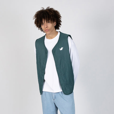 1. Male model wearing green unisex vest with Moomin logo over white shirt and jeans in studio setting