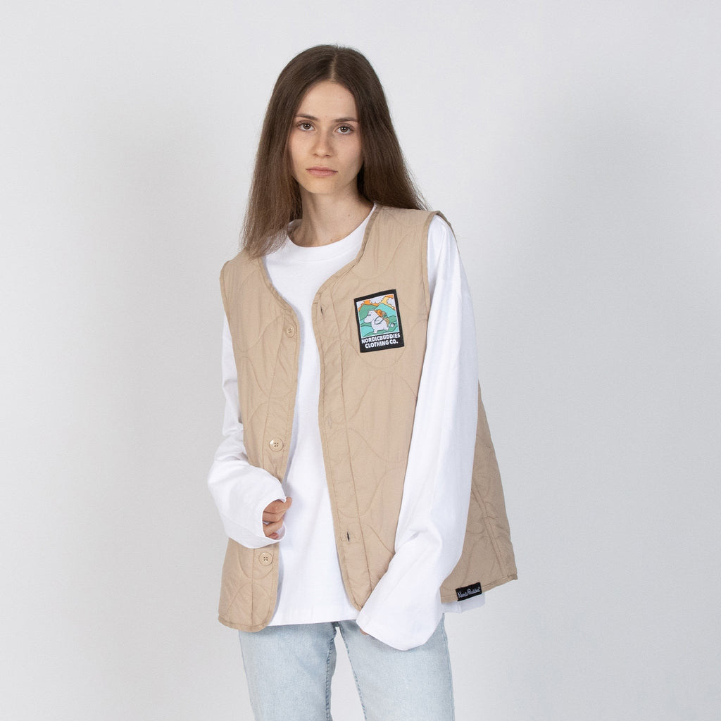 1. Woman wearing beige unisex vest with Moomintroll patch by NordicBuddies, paired with white shirt and jeans
